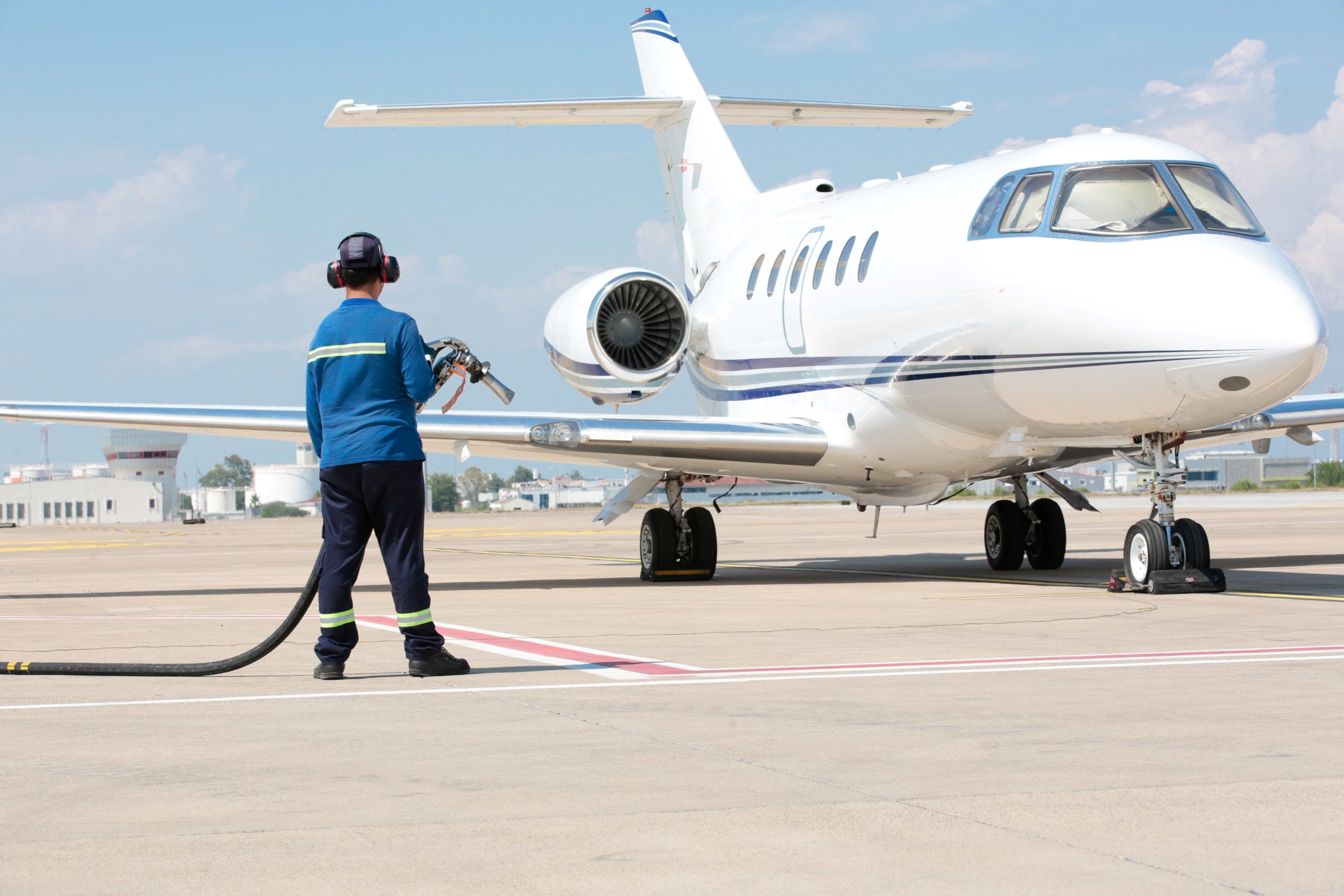 Jet on a tarmac waiting for refueling, operator standing in foreground