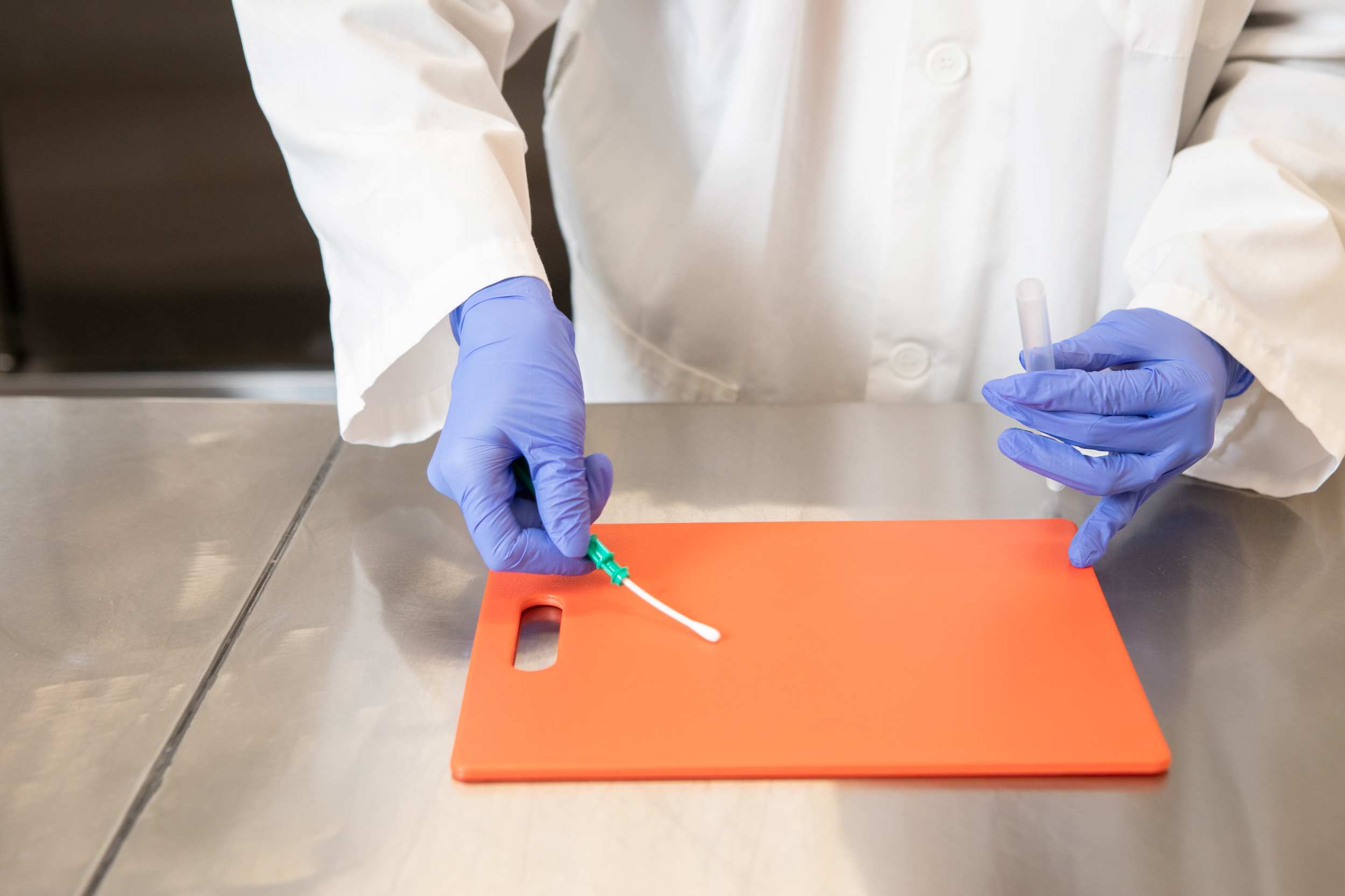 technician swabbing cutting board to validate hygiene