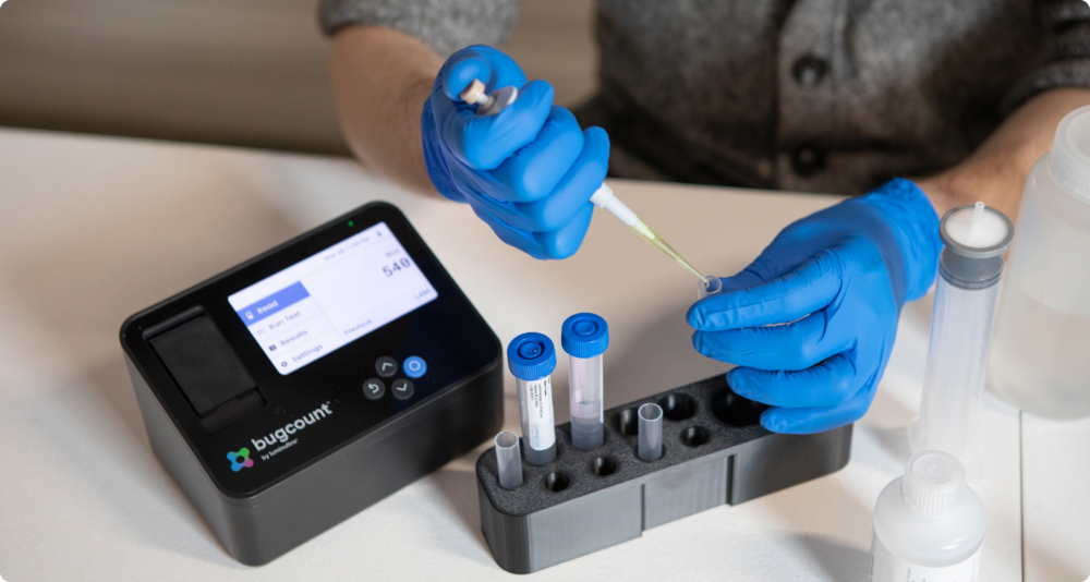gloved hands using a pipette to put fluid into a tube