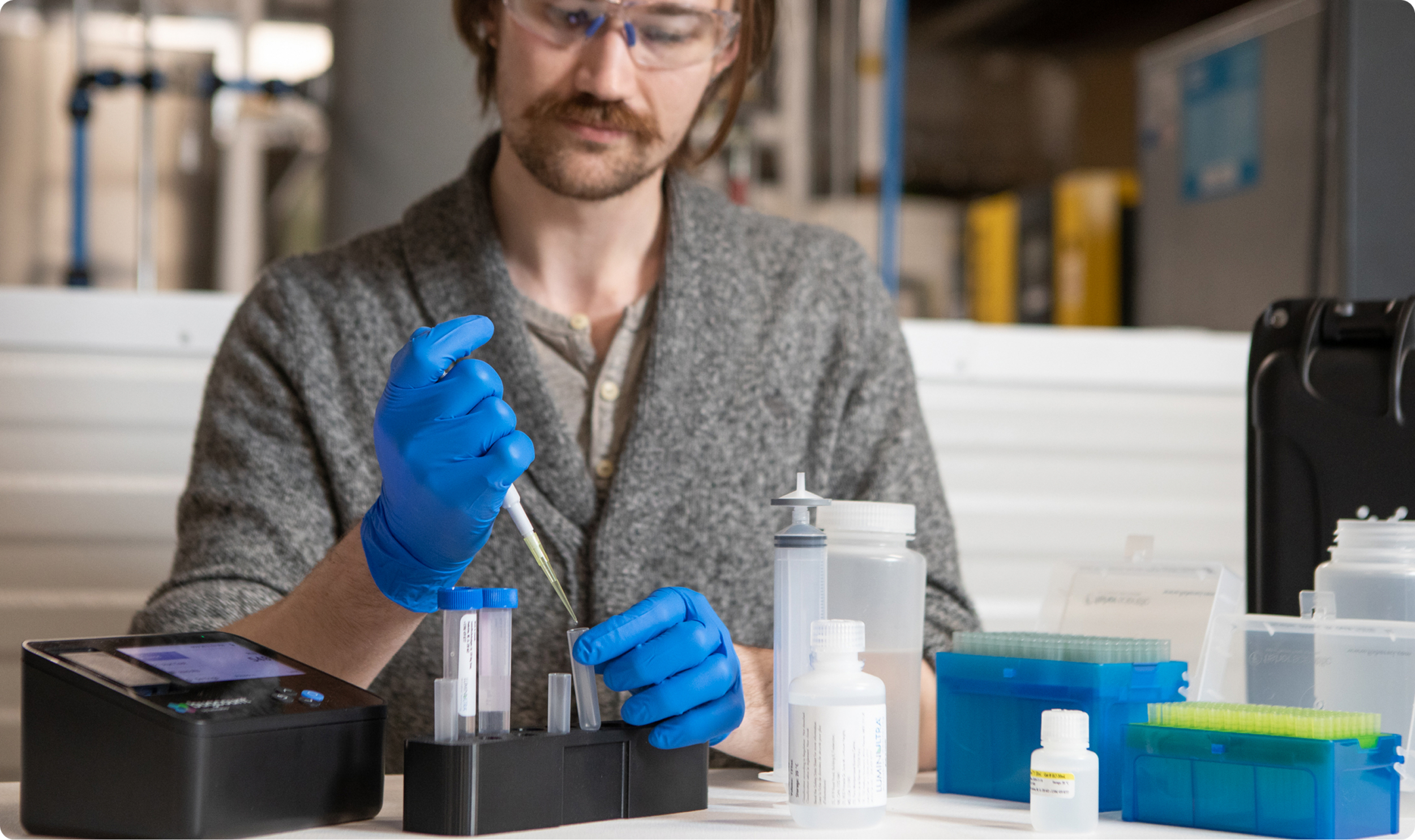 man with gloved hands using a pipette to put fluid into a tube
