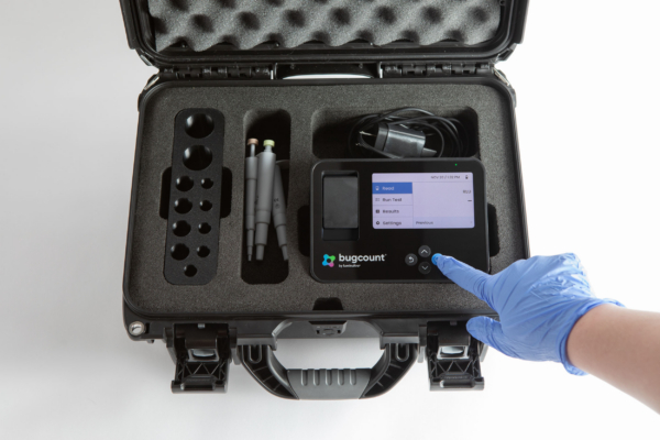hard travel case for bugcount analyzer, and person's hand pushing a button on the device