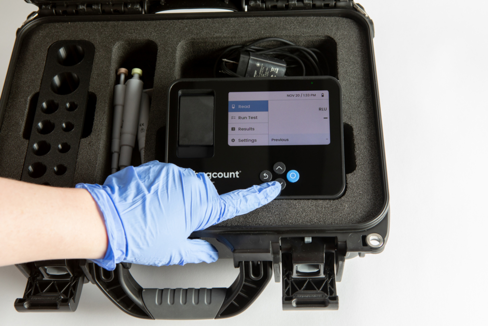 hard travel case for bugcount analyzer, and person's hand pushing a button on the device