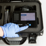 hard travel case for bugcount analyzer, and person's hand pushing a button on the device