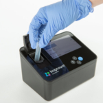 Bugcount analyzer device with gloved hand putting tube into the device for testing